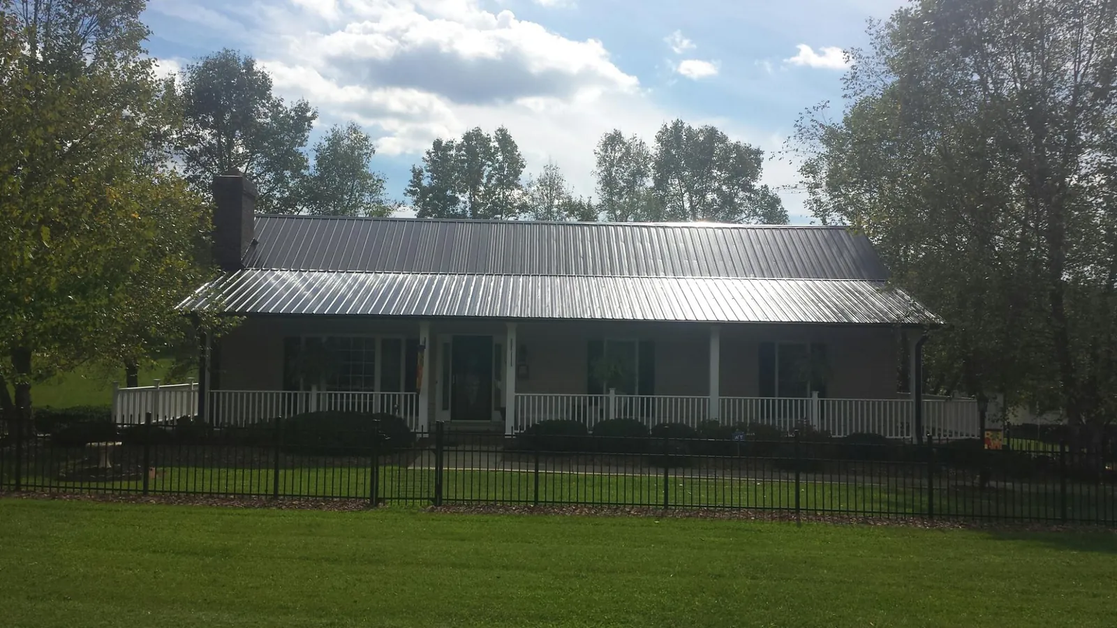 Gray metal roof on a brick ranch with a full width front porch — Gutter Guard Installation work by our crew in Elk Point